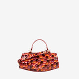 A small structured handbag with a glossy embossed pebble pattern in shades of orange, red, and brown, featuring a matching top handle and a small leather tag, shown against a plain light gray background. #color_orange