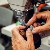 Person using a sewing machine to work on a leather item.